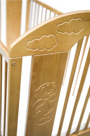Zbliżenie na frez misia i chmurek na froncie łóżeczka Teddy w kolorze naturalnego drewna